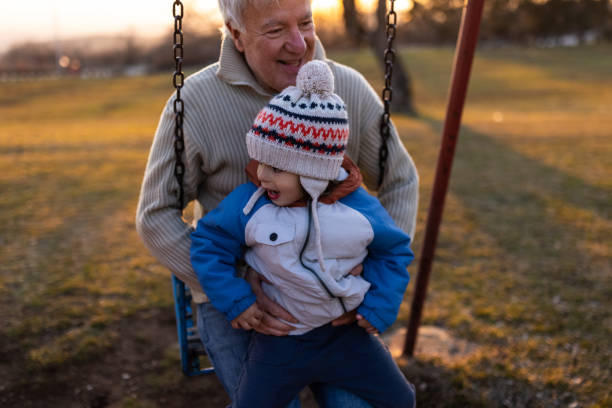 малыш мальчик наслаждается качелями с дедушкой - child swing swinging balance стоковые фото и изображения