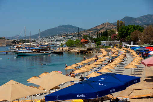 Mugla, Turkey - May 26, 2022 : View of Bodrum Beach, Aegean sea, traditional white houses, flowers, marina, sailing boats, yachts in Bodrum city town Turkey.