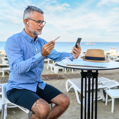 Businessman works with a smartphone on the beach on vacation. Teleworking