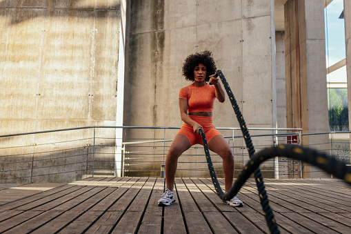 Young african american woman working out with ropes at the outdoors gym