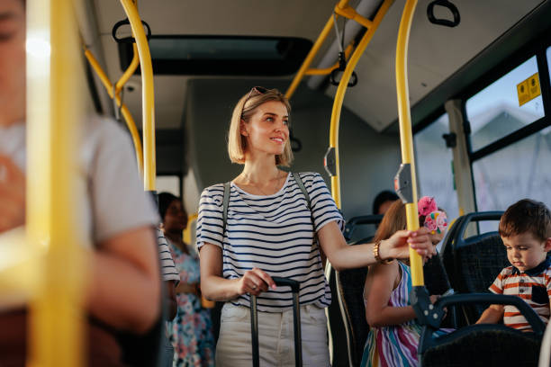 gruppo di persone che si spostano in autobus. l'attenzione si concentra sulla giovane donna con la valigia che tiene la ringhiera. - trolley bus foto e immagini stock