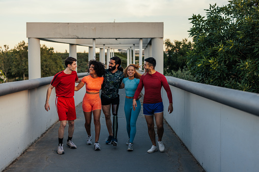 Multiracial young sportspeople standing after run outdoors, taking rest and hanging on