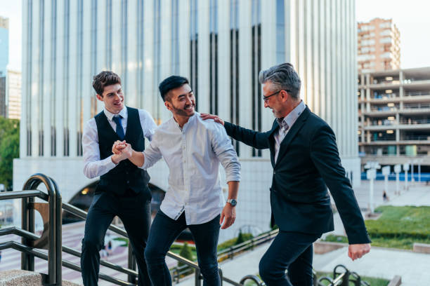 Three handsome businessmen in smart casual wear are looking at camera while standing with folded arms on a white background