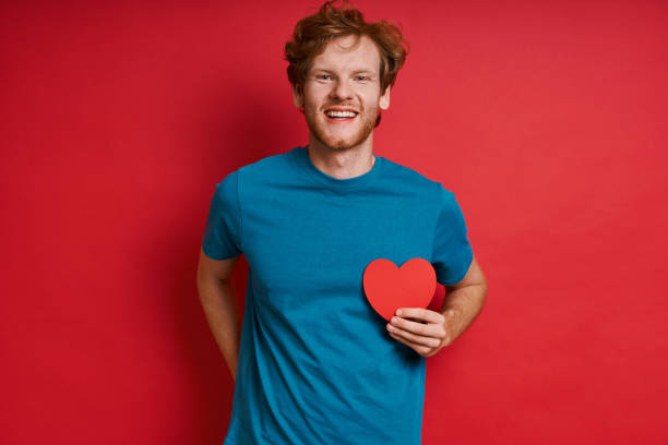 istock Happy redhead man holding red paper heart 1403082444