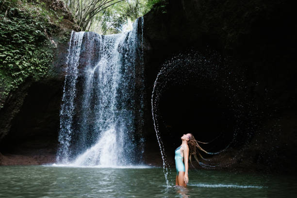 istock Woman have fun in natural pool under tropical waterfall 1403082552
