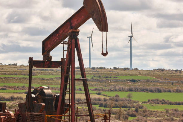 istock Oil pumping machine and windmills. Petroleum extraction. Global warming 1403083441