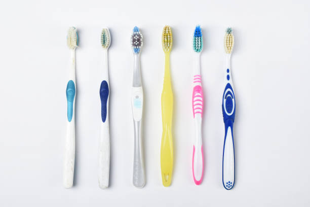 Colorful group of old toothbrushes standing next to each other on the white background, side by side old toothbrushes