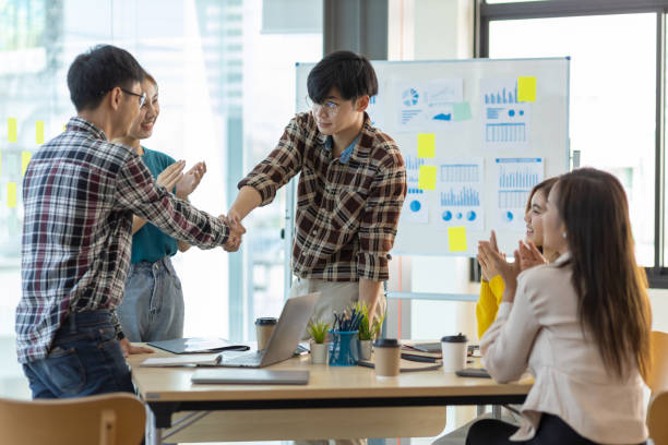 istock Young men in casual clothes shaking hands while working in a creative office. Welcome to our team. 1403085323
