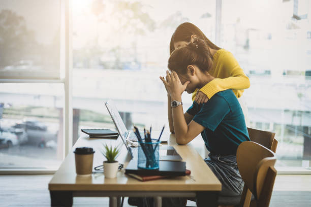 Coworker comforting stressed and discouraged woman in the office. divorce attorney near me A coworker comforting a stressed and blue woman in the office. Emotional Support stock pictures, royalty-free photos, and images.