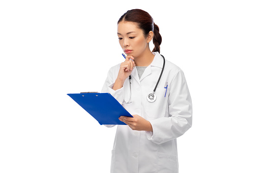 medicine, profession and healthcare concept - asian female doctor in white coat with clipboard and pen