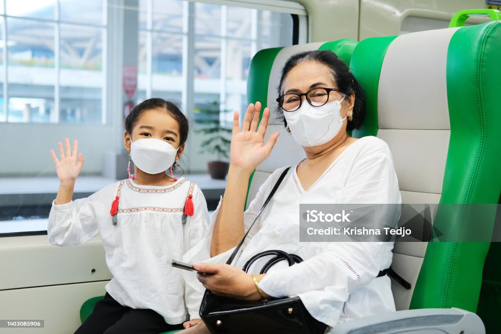 A grandma and her grand daughter waving hand to greet when sitting inside public train A grandma and her granddaughter waving hand to greet when sitting inside public train 4-5 Years Stock Photo