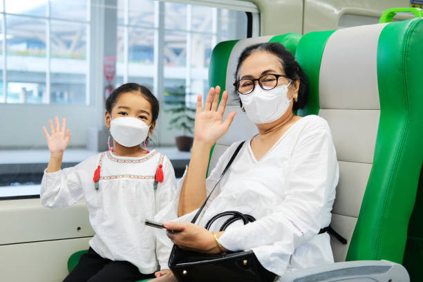 A grandma and her grand daughter waving hand to greet when sitting inside public train A grandma and her granddaughter waving hand to greet when sitting inside public train keluarga stock pictures, royalty-free photos & images