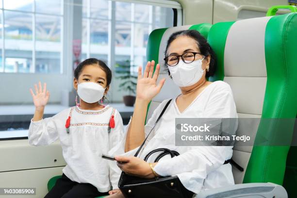 A Grandma And Her Grand Daughter Waving Hand To Greet When Sitting Inside Public Train Stock Photo - Download Image Now