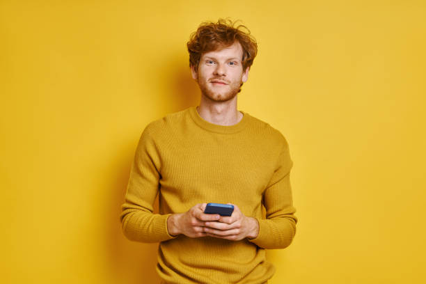 Handsome redhead man holding mobile phone stock photo