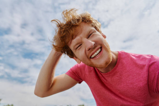 istock Cheerful young redhead man looking at camera and smiling with sky in the background 1403087277