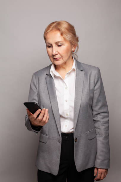 mujer seria de 60 años con retrato de teléfono inteligente - senior adult 60 65 years people occupation fotografías e imágenes de stock
