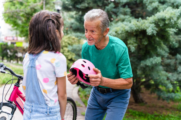 little girl learning ride a bike with grandfather - active seniors enjoyment driveway vitality imagens e fotografias de stock