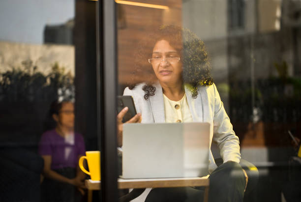 istock Businesswoman using laptop and phone at cafe 1403088720