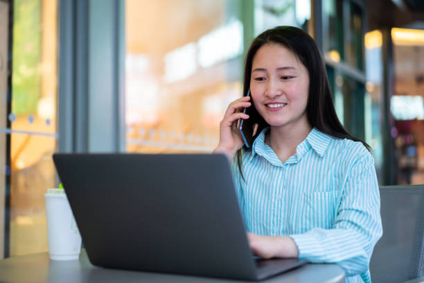 istock Asian young woman using laptop in coffee shop 1403090438