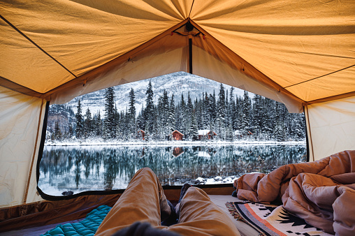 Traveler man relaxing in large tent with cottage in the forest at Lake O'hara on winter