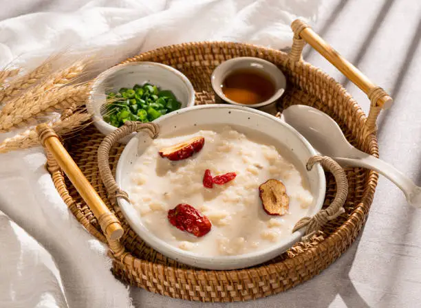 Congee barley and soymilk congee with spring onion in a dish side view on grey background
