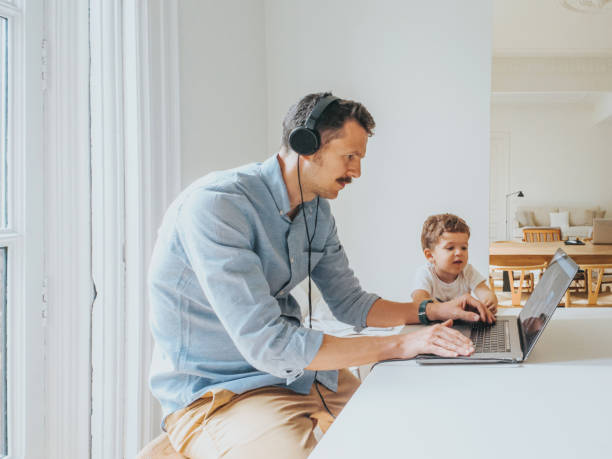 istock Father working at home while taking care of his 1403093472