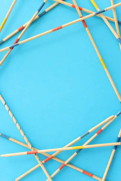 Mikado game over blue background. Wooden sticks that create a graphic image and a geometric frame