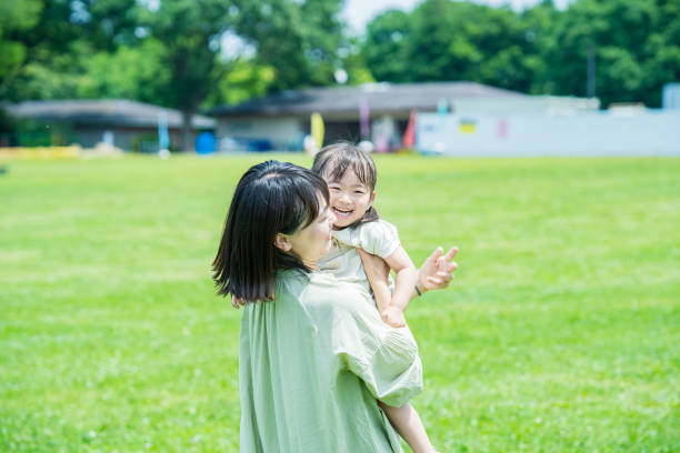madre y su hija abrazadas en el parque - park child asia lifestyles fotografías e imágenes de stock