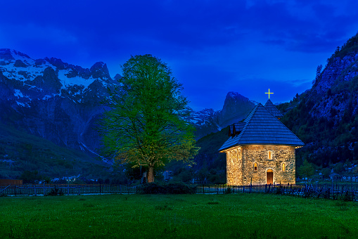 Church in the Thethi Village and snow capped mountains, at the dusk, in the Theth Valley, Albania.