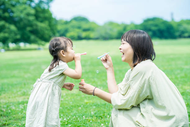 シャボン玉で遊んでいる母と娘 - child facial expression asian and indian ethnicities asia ストックフォトと画像