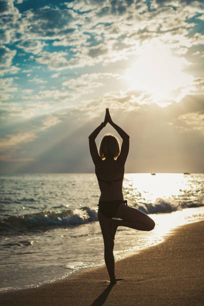 istock Woman standing in a Tree position on the beach 1403097582