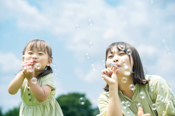 istock mother and her daughter playing with soap bubbles 1403097611