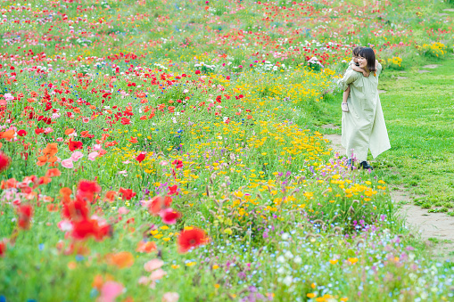mother and her daughter strolling in the flower field at the park