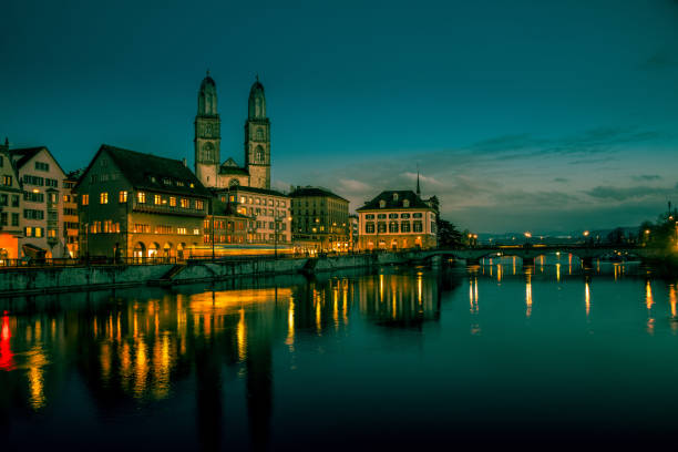 hermoso río limmat e iglesia grossmünster en zurich por la noche, suiza - grossmunster cathedral fotografías e imágenes de stock