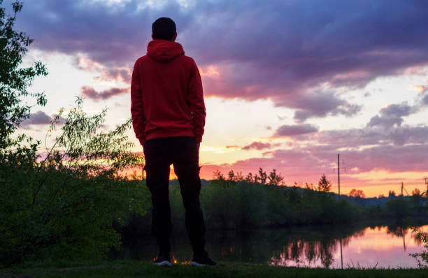 A man alone admires a beautiful summer sunset by the river