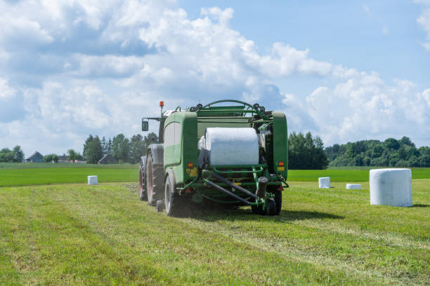 Baler wrapper Baler wrapper working on the green field hay baler stock pictures, royalty-free photos & images