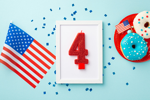 USA Independence Day concept. Top view photo of photo frame with number 4 candle national flag plate with glazed donuts and confetti on isolated pastel blue background