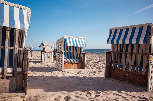 Rows of Strandkorb beach-chairs for hire the seafront. A Strandkorb is providing shelter from sun and wind.