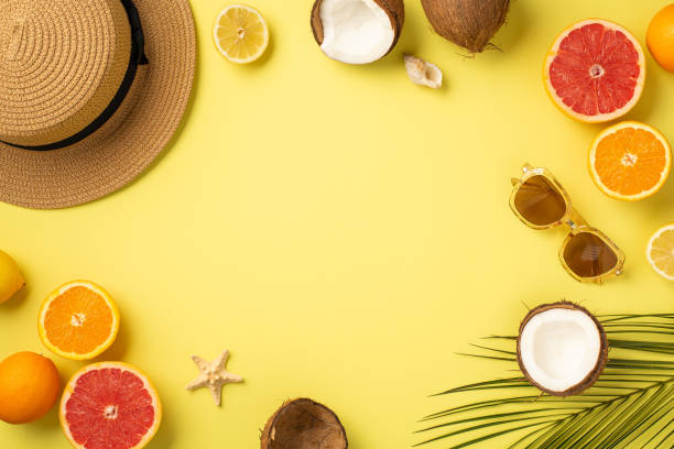 istock Summer concept. Top view photo of sunglasses shell starfish sunhat cracked coconuts cut oranges lemons grapefruits and green palm leaves on isolated yellow background with copyspace in the middle 1403102797