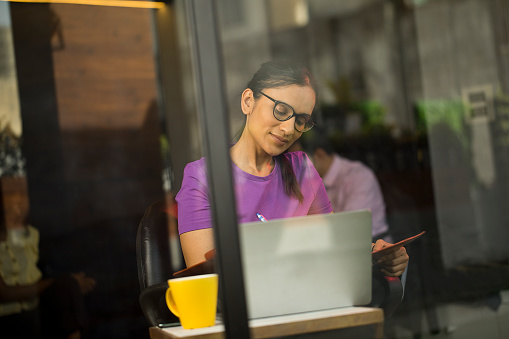 Businesswoman analyzing documents while working at coffee shop