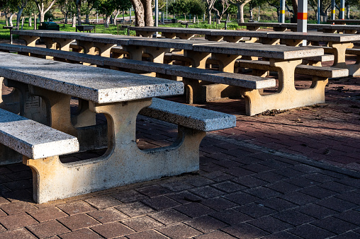 Empty tables with picnic benches in the park Sunny day perspective. Close-up.