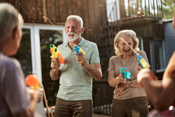 istock Happy senior couples having fun during water gun fight on a terrace. 1403104680