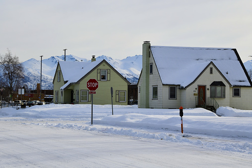 Anchorage, Alaska, USA: snow covered houses on a residential street - Chugach Mountains in the background