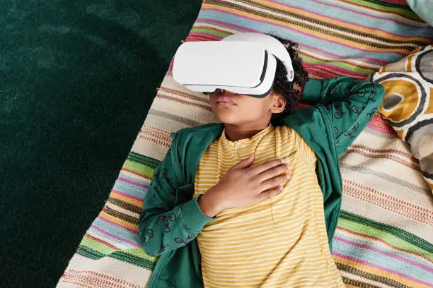 Photo of Boy relaxing at home with VR goggles