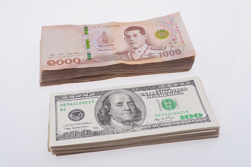 One thousand Thai Baht (THB) and one hundred U.S. dollars (USD) banknotes stack, Isolated on white background. Economic movements of Thailand Idea. Background image with high resolution.