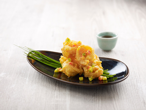 Crispy fried Crystal Prawns tossed with Salted Egg Yolk with chopsticks served in a dish isolated on mat side view on grey background