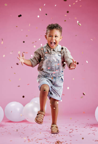 istock A cute little mixed race boy  celebrating and winning against a pink copyspace background in a studio. African child looking excited at a gender reveal party with confetti and balloons 1403120461