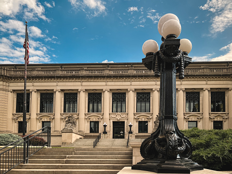 Front View of the Illinois Supreme Courthouse in Springfield, IL, USA on a Summer day. Vintage style light fixture in the foreground. American flag stands in front of this majestic building.