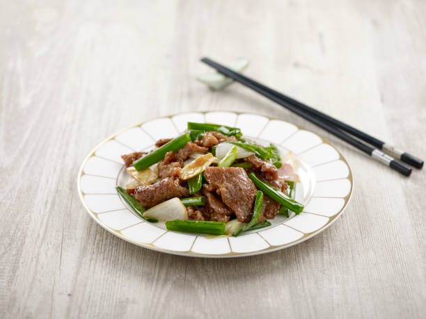 istock Stir-fried Sliced US Marbled Beef with Ginger and Spring Onion with chopsticks served in a dish isolated on mat side view on grey background 1403122923