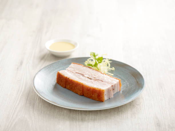 Crackling Pork Belly Served in a dish isolated on wooden board side view on grey background